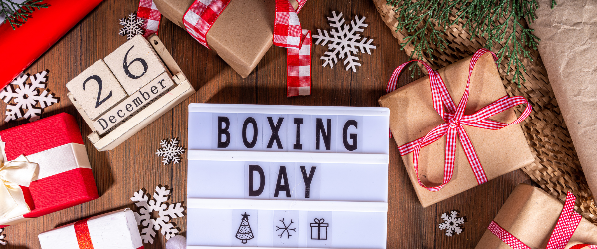 Boxing Day Sale display featuring discounted Christmas décor, lights, tableware, gifts, wrapping supplies and pet toys arranged on festive shelves.