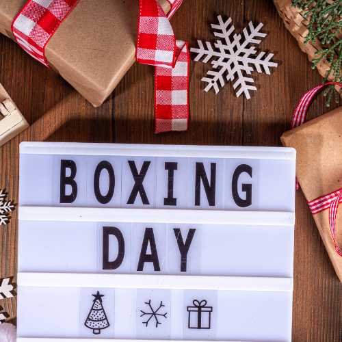 Boxing Day Sale display featuring discounted Christmas décor, lights, tableware, gifts, wrapping supplies and pet toys arranged on festive shelves.