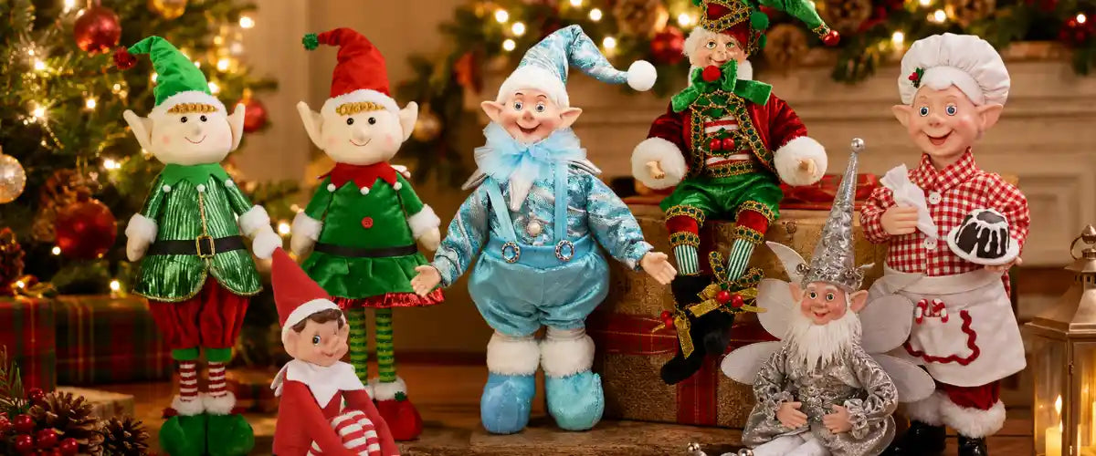 Christmas Elves Collection featuring festive elf figurines in traditional red, green and gold outfits, displayed with holiday greenery, ornaments and Christmas gifts.