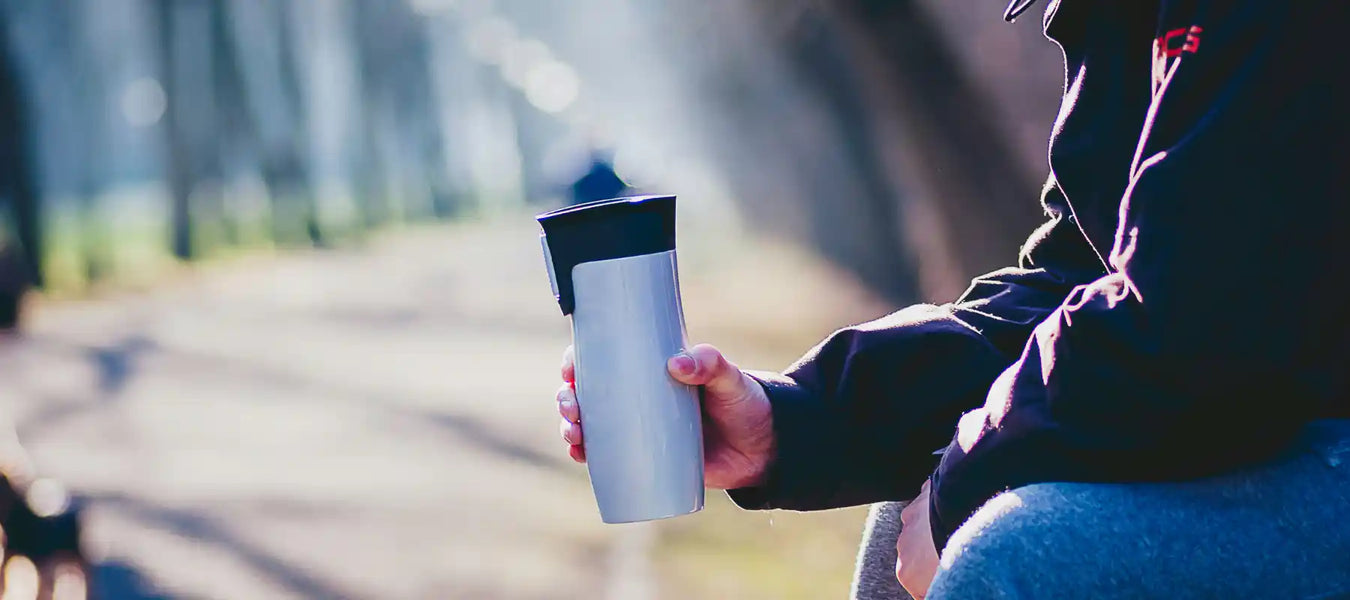 Reusable insulated travel cup outdoors, ideal for hot or cold drinks on the go.