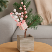 Decorative plant with pink and white berries in a wooden pot on a table. – thumbnail