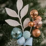 Decorative ornament with metallic balls and a leaf-like design on a blurred green background