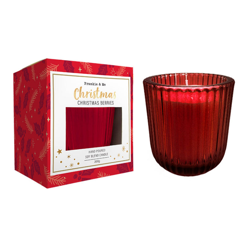 Red ribboned Christmas candle lit among seasonal decorations.