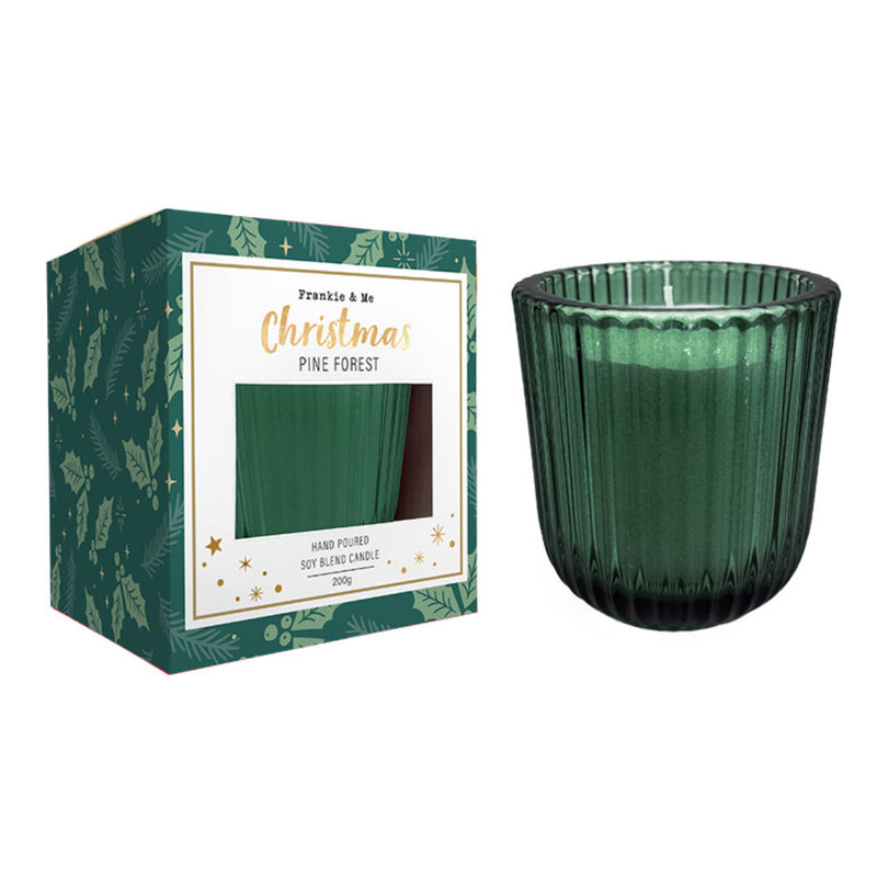 Green ribboned Christmas candle glowing on a decorated table.