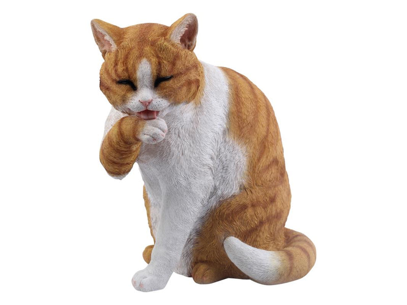 Realistic sitting cat cleaning paw statue