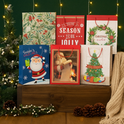 Medium Christmas gift bags with assorted festive designs made from FSC Mix paper