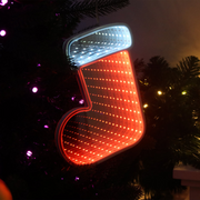 Infinity mirror Christmas boot with glowing LED lights hanging on a holiday-themed wall