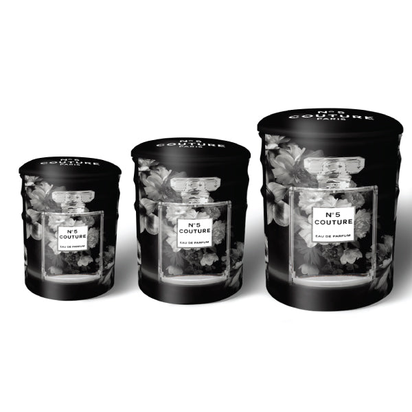 A set of three round tin ottomans featuring chic perfume and fashion designs.