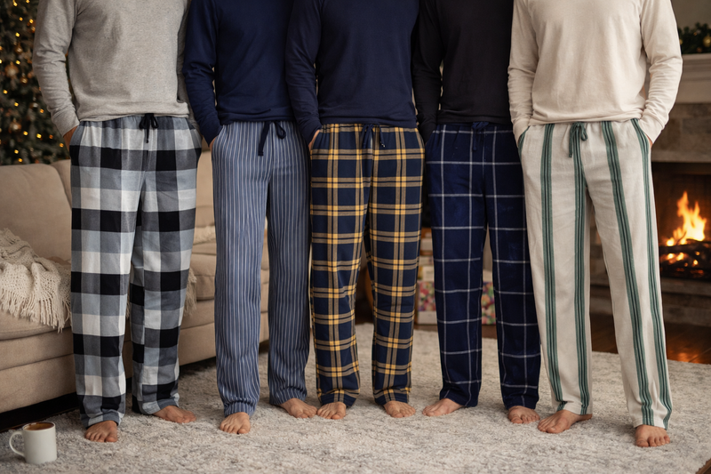 Five people wearing lounge pants standing in a row in a cozy living room.