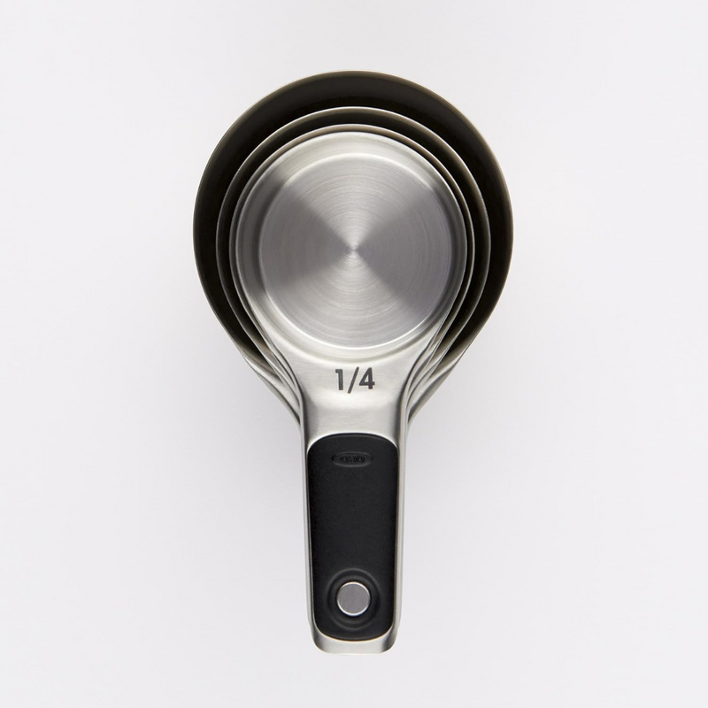OXO Good Grips 4-Piece Stainless Steel Measuring Cup Set with etched markings, magnetic bases, and non-slip handles.