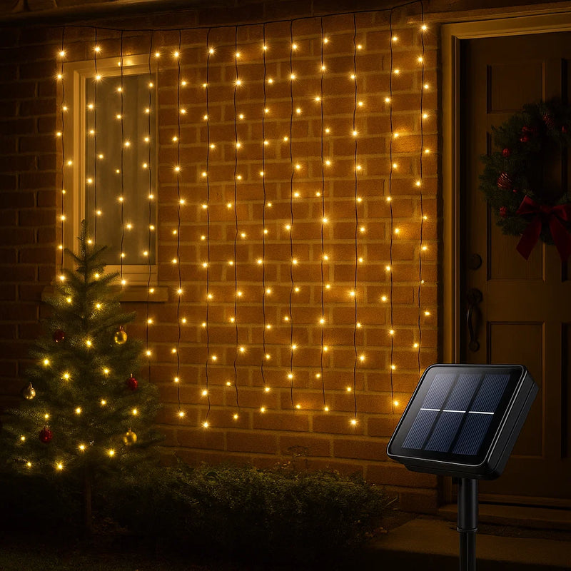 Solar powered warm white 160 LED curtain light hanging outdoors, glowing in a cascading pattern