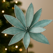 Decorative green poinsettia flower on a blurred Christmas tree background