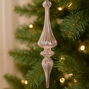 Decorative pink finial ornament on a Christmas tree with blurred lights in the background