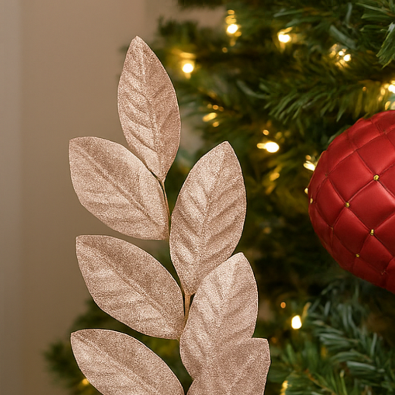 Decorative leaf ornament in front of a Christmas tree with red ball