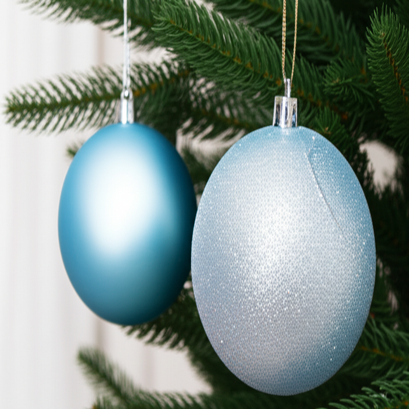 Two blue Christmas ornaments hanging on a tree branch.