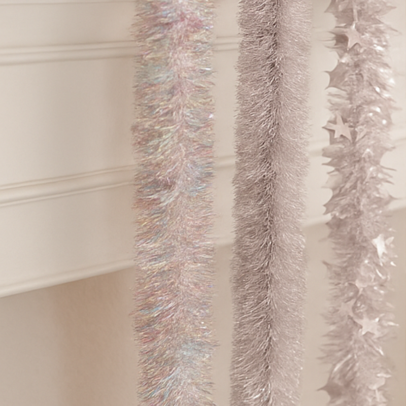 Decorative tinsel garlands with star accents on a neutral background