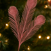 Decorative feather ornament on a Christmas tree with blurred lights in the background