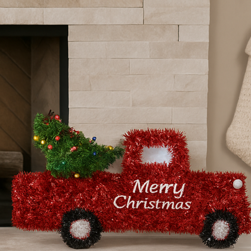 Decorative red Christmas truck with a tree in the bed, sitting in front of a fireplace.