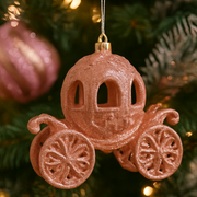 Decorative pink carriage ornament hanging on a Christmas tree.