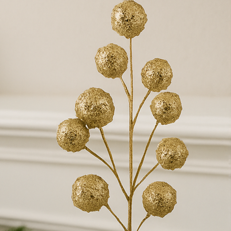 Decorative gold branch with spherical ends on a neutral background