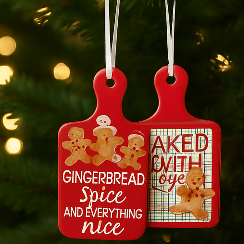 Two red gingerbread-themed Christmas ornaments hanging on a tree with lights in the background.