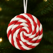 Red and white rope ball ornament hanging on a Christmas tree.