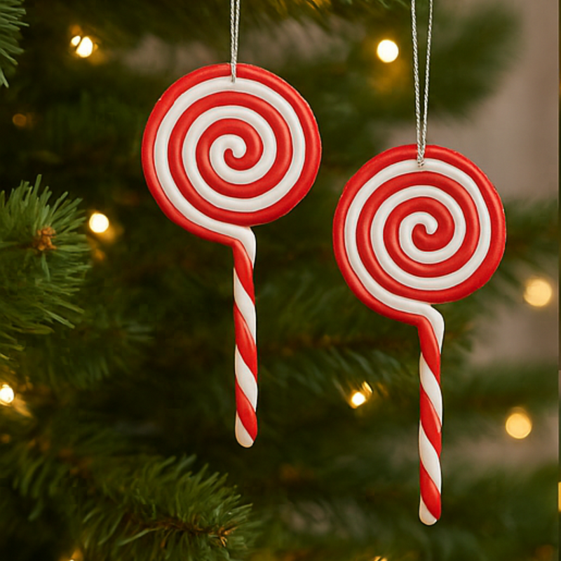 Two red and white lollipop-shaped Christmas ornaments hanging on a tree.