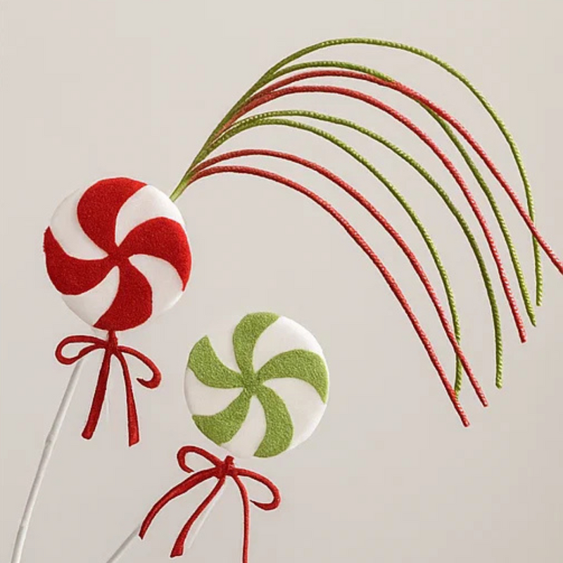 Decorative lollipops on sticks with red and green ribbons on a light background