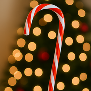 Red and white striped candy cane against a blurred bokeh background of lights