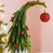Decorative Christmas garland with red berries and a red ornament on a pink background