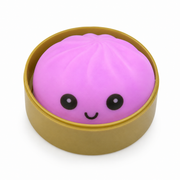 Pink bun-shaped stress reliever toy with a smiling face in a brown container on a white background – thumbnail
