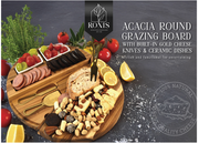 Acacia round grazing board with food items and cutlery on a dark background, featuring Ronis brand. – thumbnail