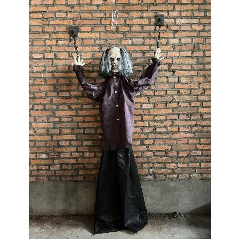 Child-sized animatronic prop of a hanging cuffed man with grey hair, red glowing eyes, and shackled arms, suspended as a Halloween decoration.

