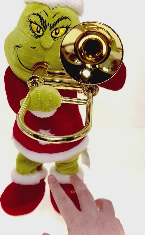 Plush Grinch figure standing and playing a trombone, wearing a Santa suit with animated features.