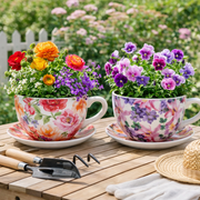 Two floral teacups filled with flowers on a wooden table outdoors. – thumbnail